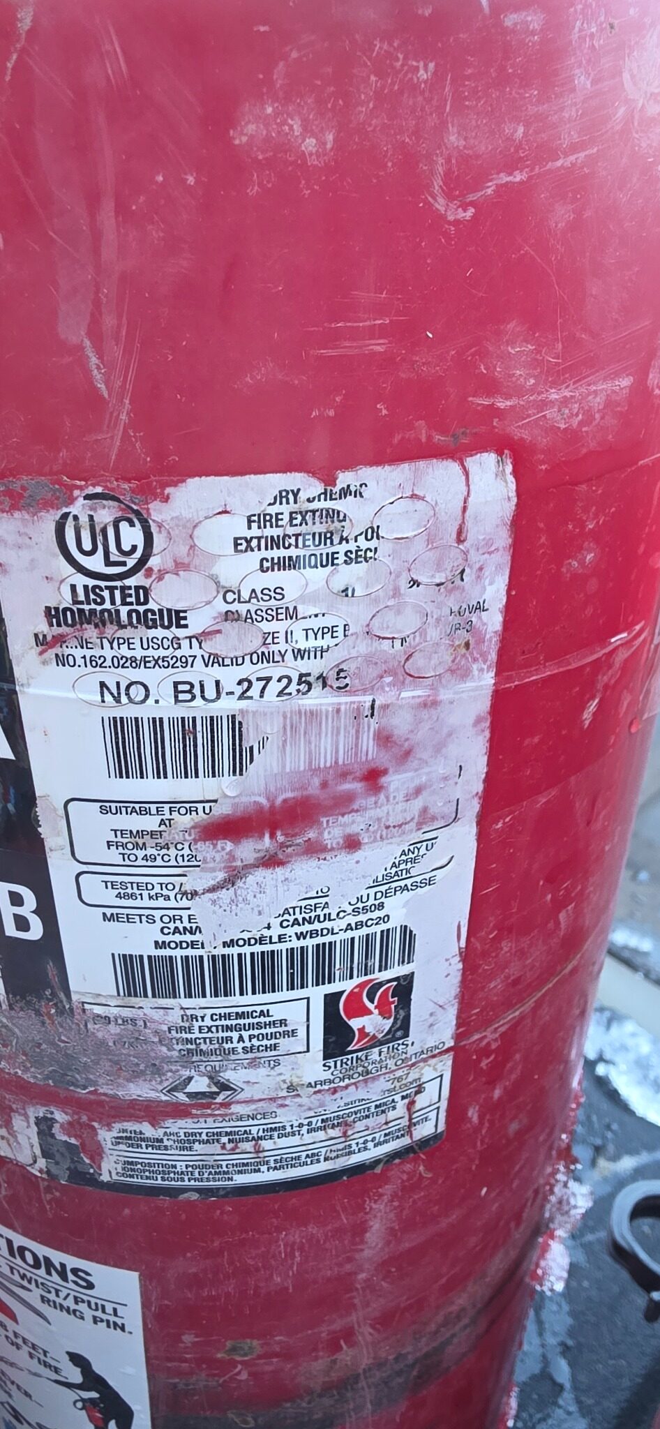 Fire extinguisher label with serial number damage from hose band abrasion — real field photo