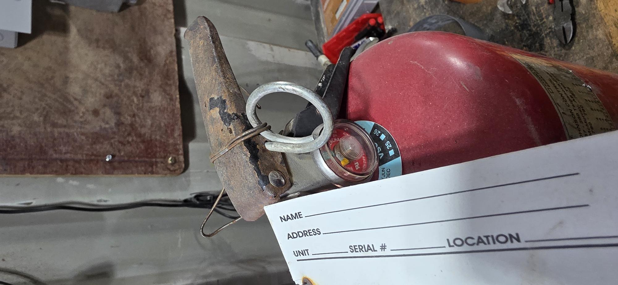 Fire extinguisher safety pin wrapped in multiple winds of steel wire — real field finding from Northern Alberta industrial inspection